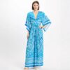 Model wearing a blue geometric print maxi dress with a plunging V-neck, wide kimono sleeves, and a tied waist, paired with espadrille sandals.