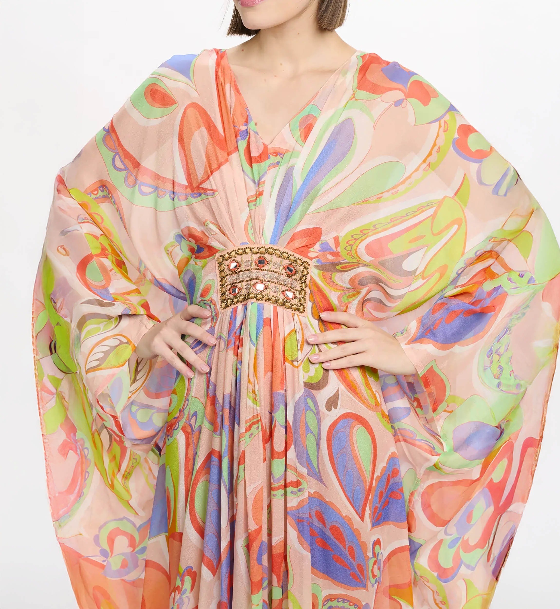 Model wearing a sheer, colorful abstract-print kaftan with a gold jeweled belt at the waist.