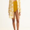 Model wearing a mustard-yellow one-piece swimsuit under a cream cover-up with a yellow palm print.