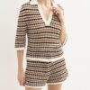 Woman wearing a cream, brown, and black striped knitted polo sweater with matching shorts set.