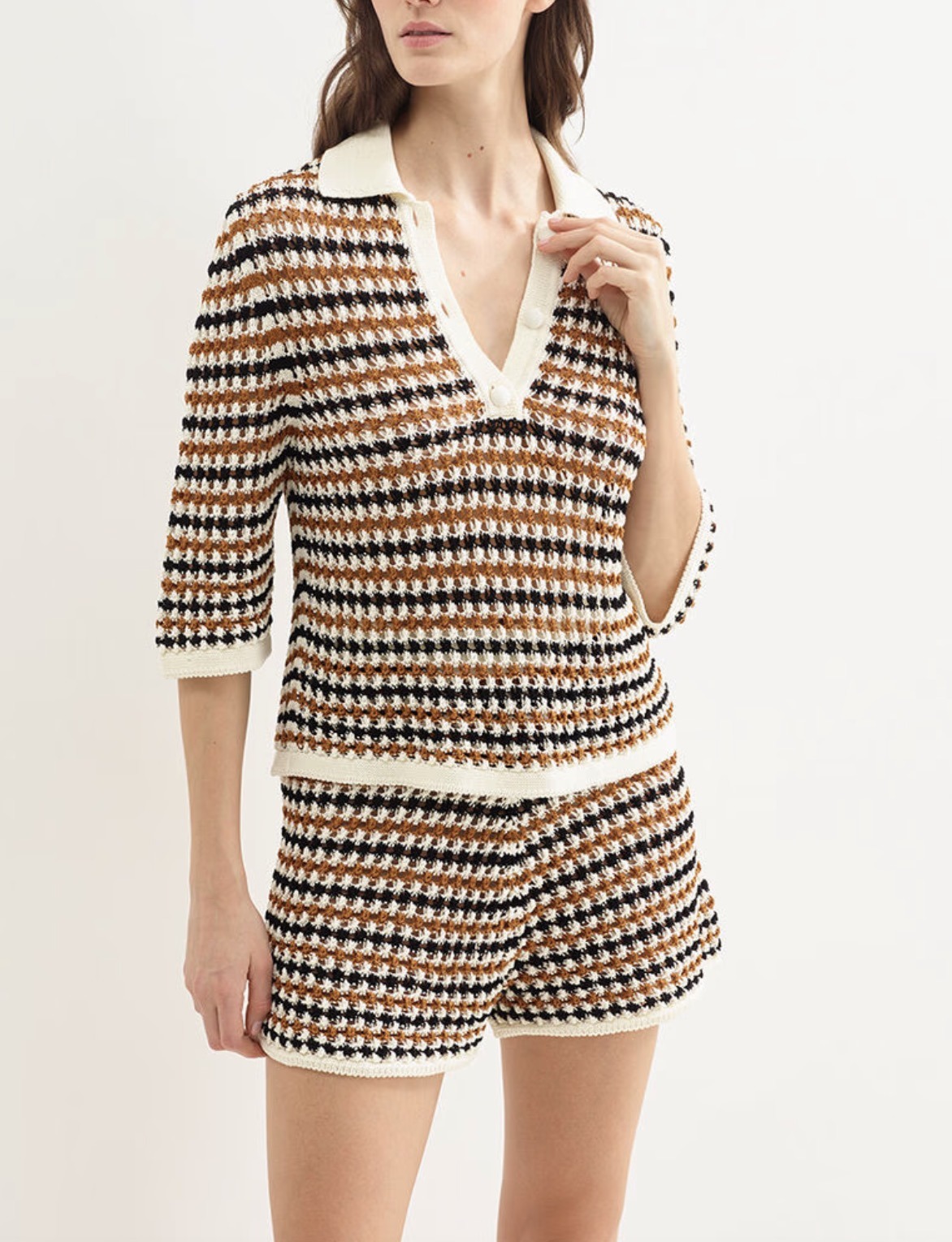 Woman wearing a cream, brown, and black striped knitted polo sweater with matching shorts set.