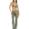 Woman in turquoise bikini top and sheer striped pants, wearing a green cap with a gold star and gold sandals, standing with one hand on her hip.