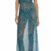 Model wearing a turquoise leopard-print maxi dress with a sheer overlay and a side slit, standing in sandals against a white background.