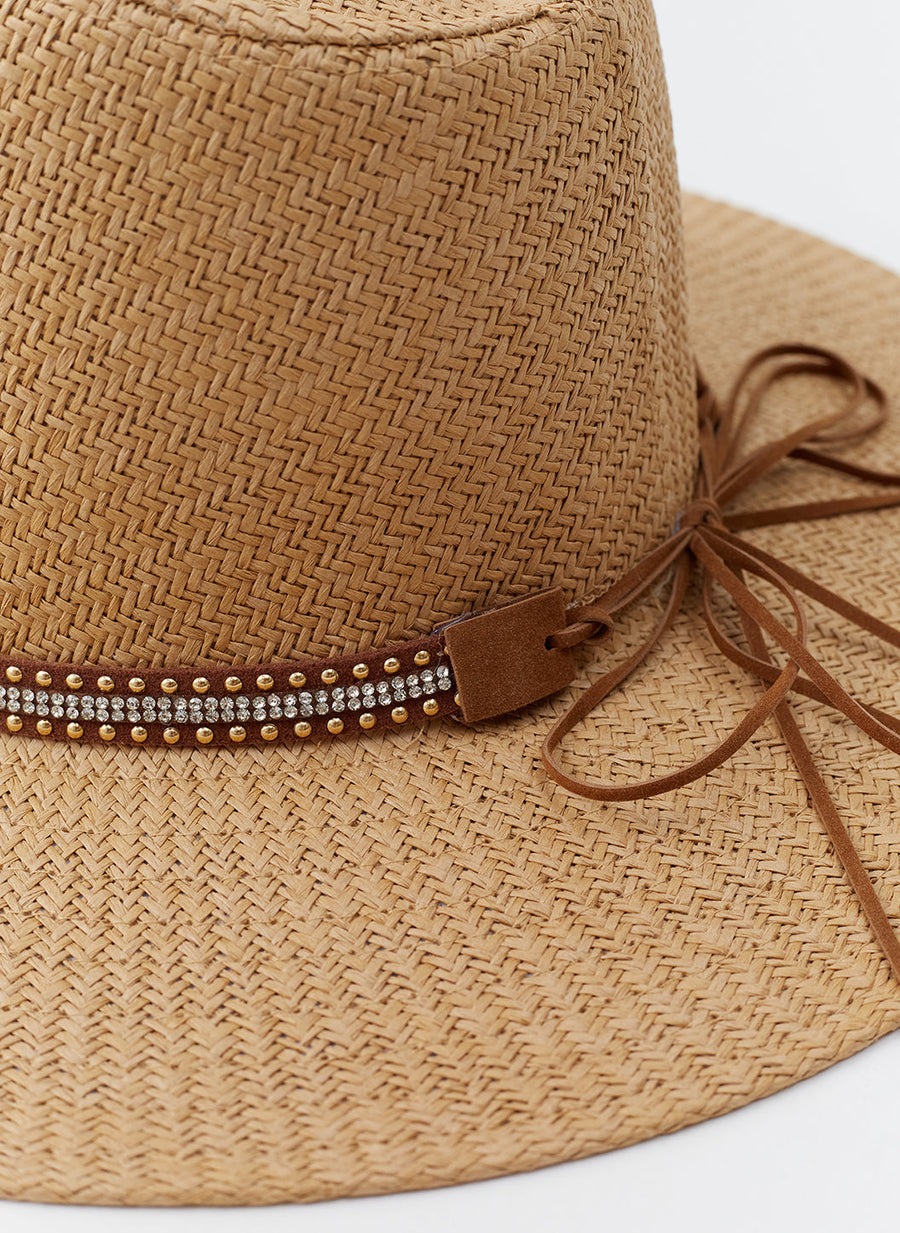 Close-up of a woven straw hat with a beaded and leather band around the crown.