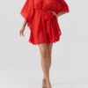 Red lace kimono-style cover-up with a waist belt and scalloped hem, worn over a swimsuit by a model in sandals.
