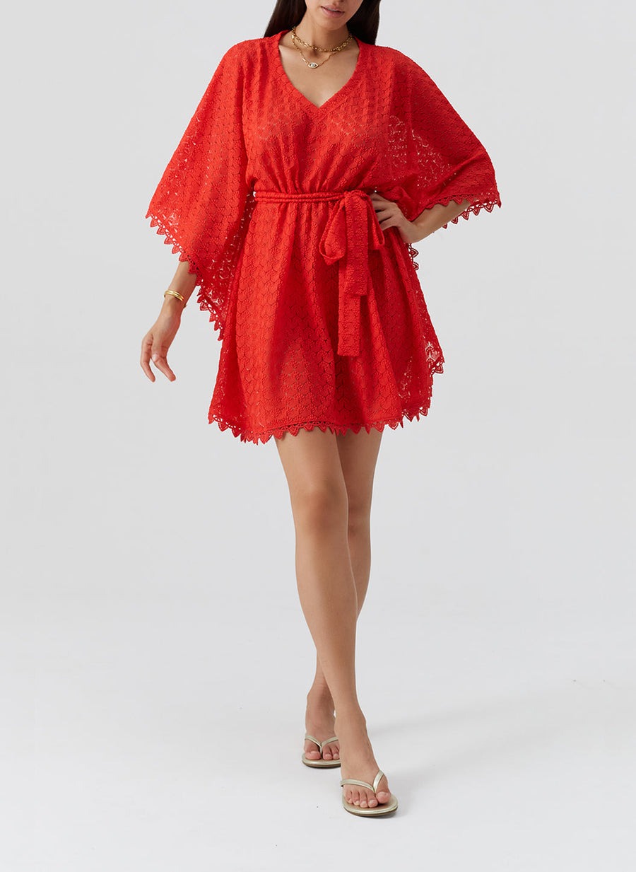 Red lace kimono-style cover-up with a waist belt and scalloped hem, worn over a swimsuit by a model in sandals.