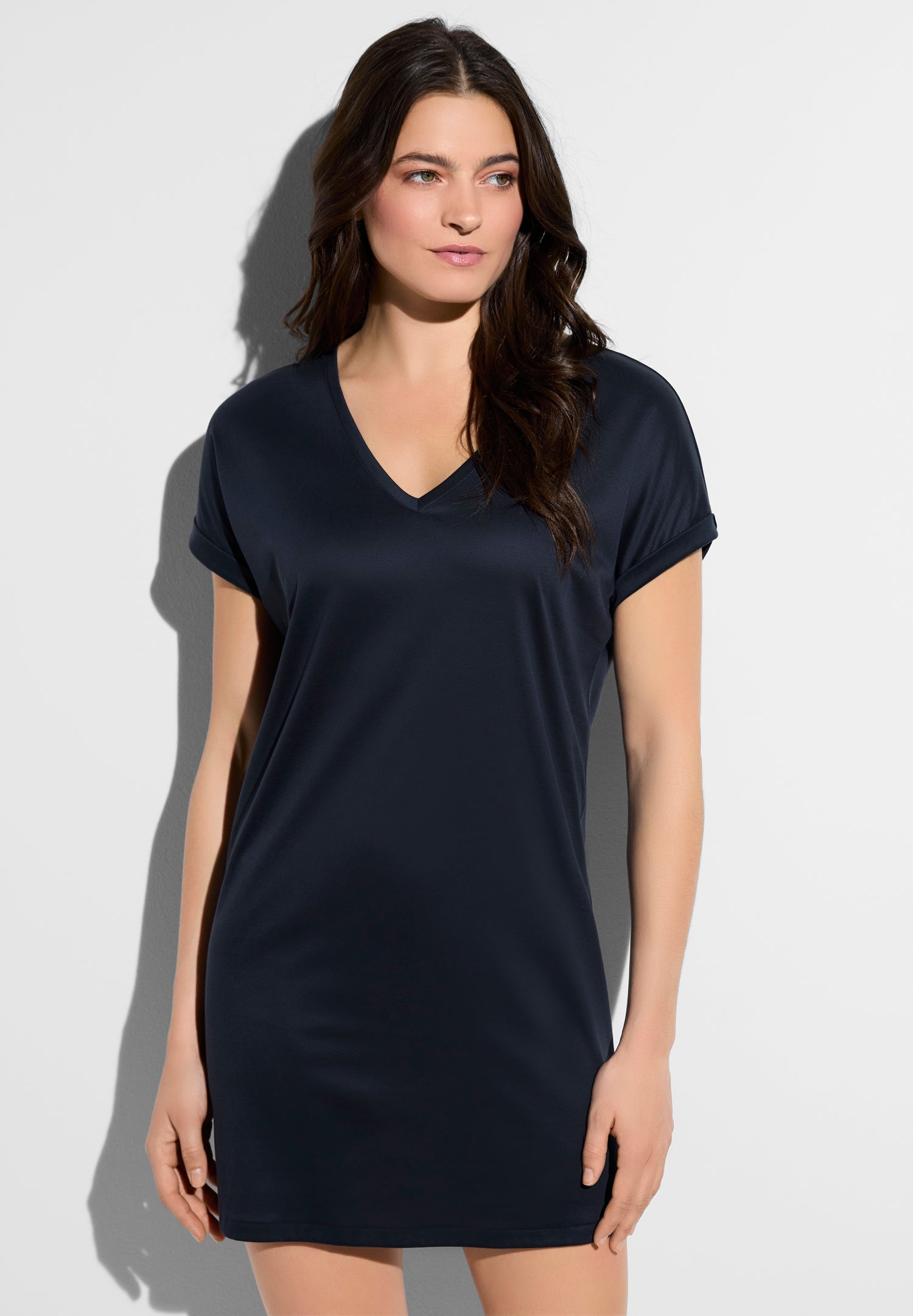 Woman in a navy V-neck short-sleeve top against a light wall outside the frame edge of the image