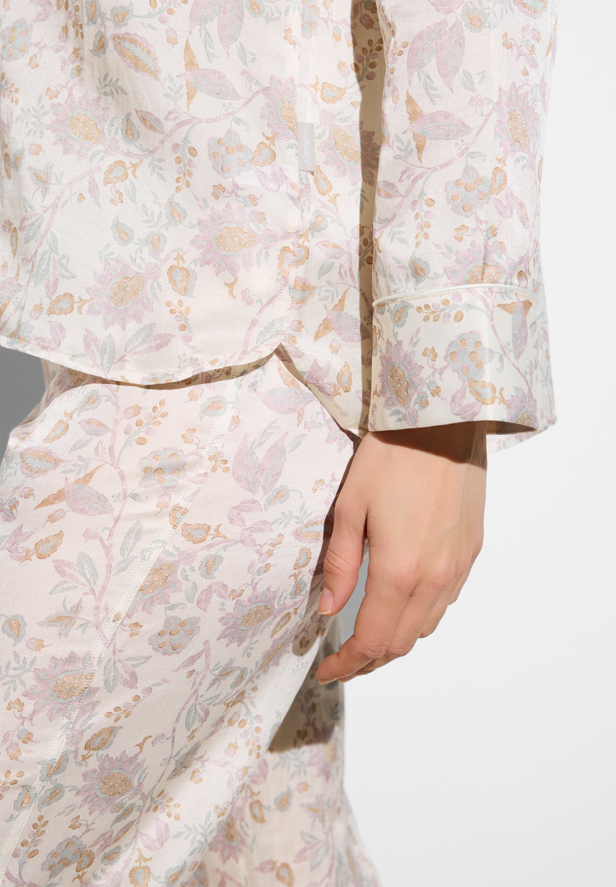 Close-up of pastel floral pajama fabric with pink, peach, and lavender flowers and a cuff detail on the sleeve.