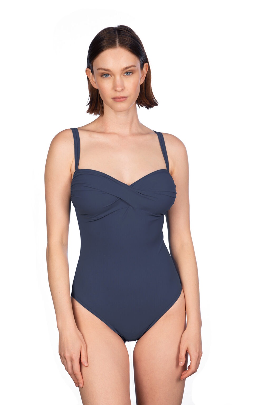 Model wearing a navy blue one-piece swimsuit with twisted front detailing, standing against a white background.