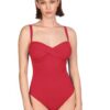 Woman in a red one-piece swimsuit with a twisted front, standing against a white background.